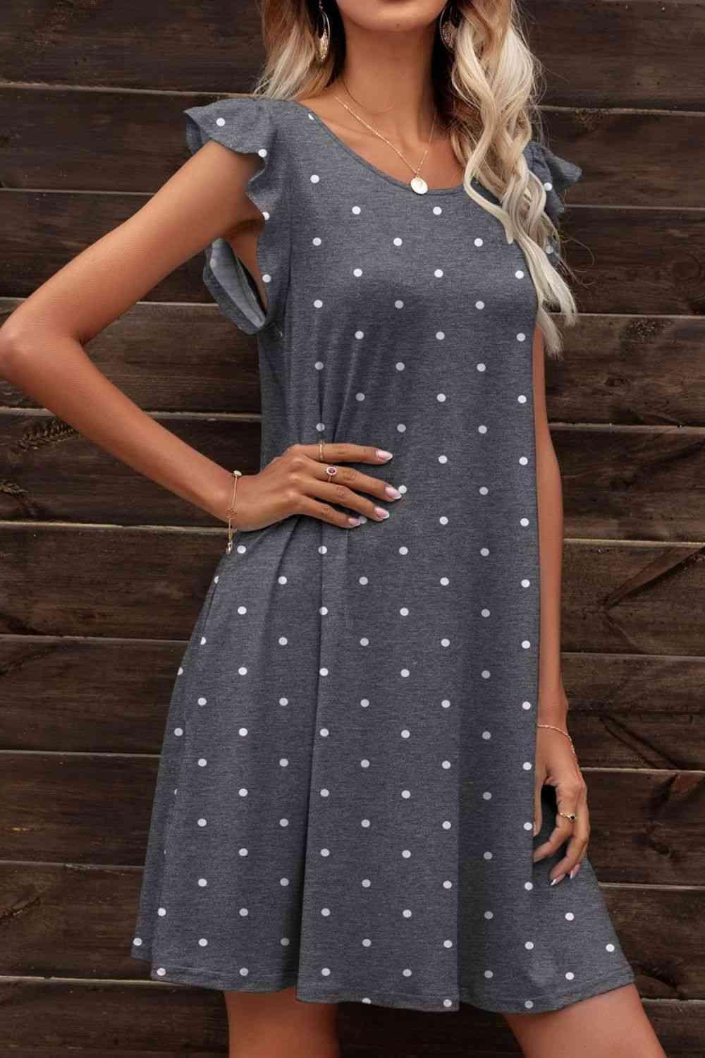 a woman wearing a gray dress with white polka dots