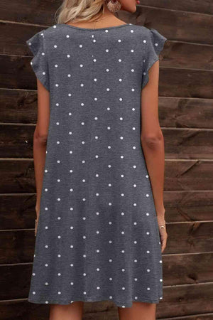 a woman wearing a grey dress with white polka dots