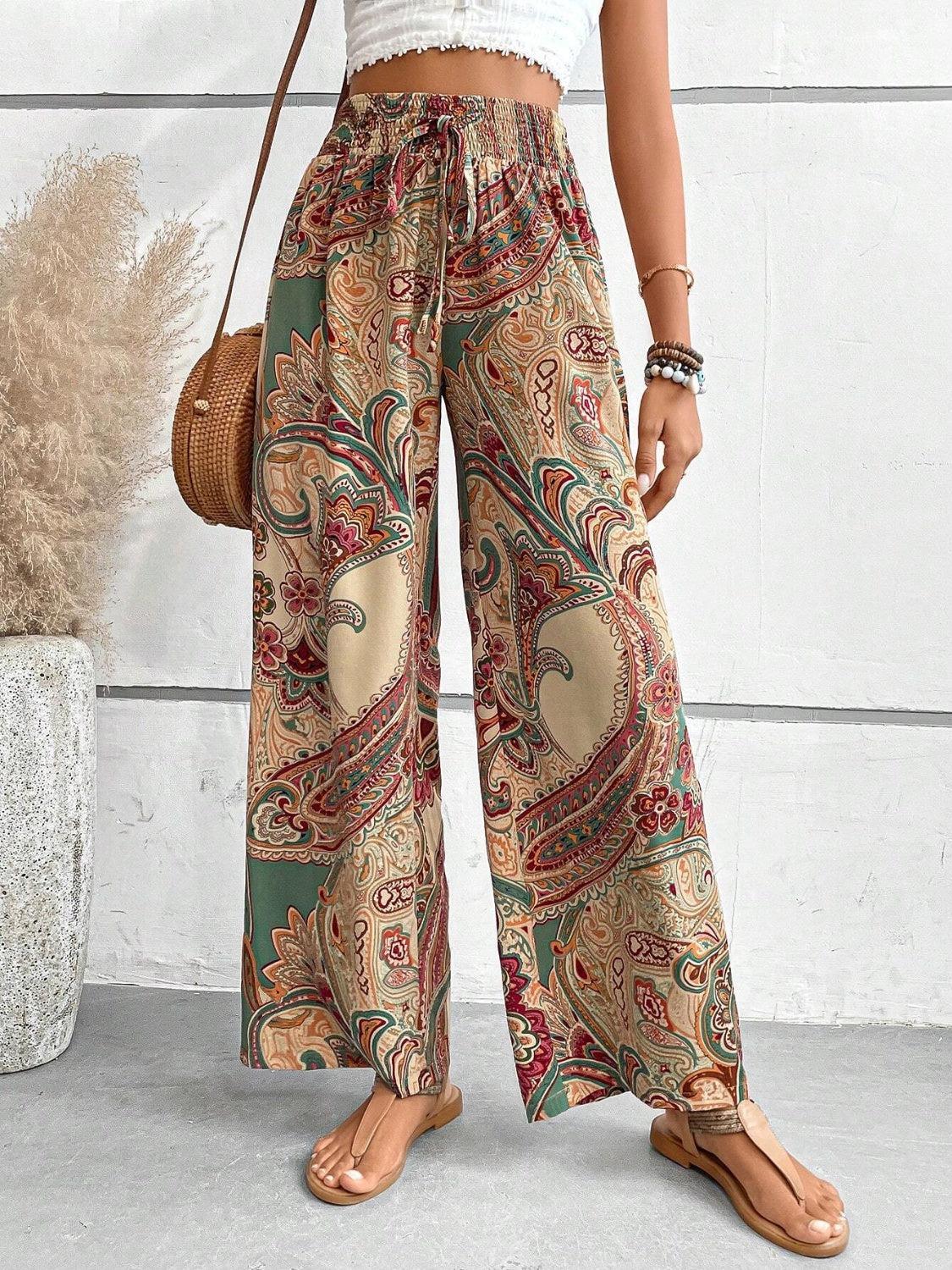 a woman wearing a white top and patterned pants