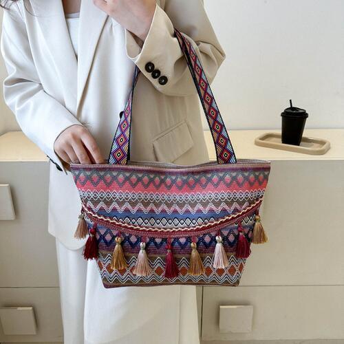 a woman holding a multicolored bag with tassels