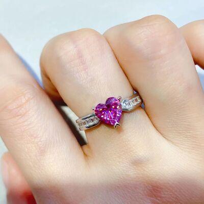 a close up of a person's hand holding a ring with a heart shaped