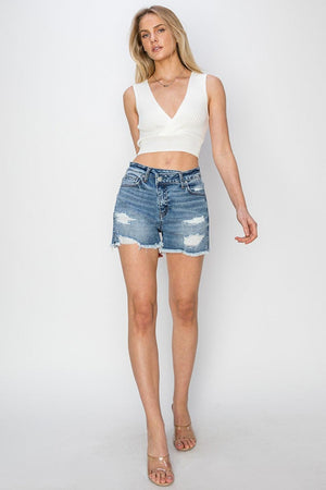 a woman wearing a white top and denim shorts