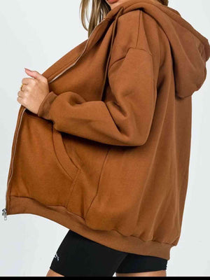 a woman wearing a brown hoodie and black shorts