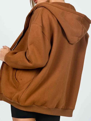 a woman wearing a brown hoodie and black shorts