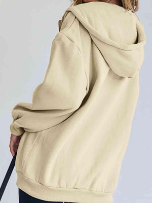 a woman in a beige hoodie holding a black umbrella