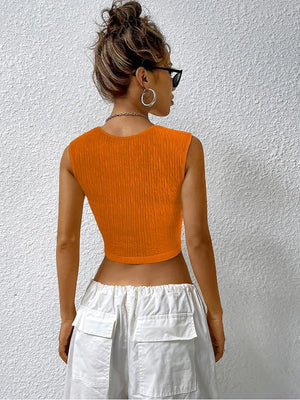 a woman wearing an orange crop top and white shorts