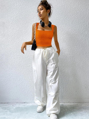 a woman in an orange top and white pants