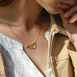 a woman wearing a necklace with a heart on it
