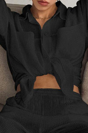 a woman sitting on a couch wearing a black shirt and pants