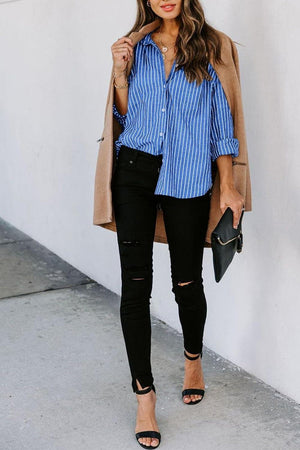 a woman wearing a blue striped shirt and black ripped jeans