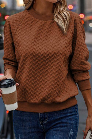 a woman in a brown sweater holding a cup of coffee