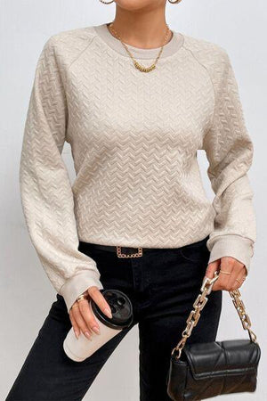 a woman holding a black purse and wearing a white sweater