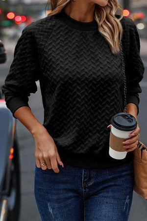 a woman in a black sweater holding a cup of coffee