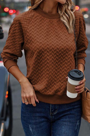 a woman in a brown sweater holding a cup of coffee