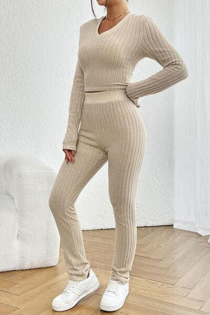 a woman standing in a room wearing a sweater and pants