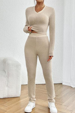 a woman standing in a room wearing a sweater and pants