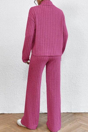 a woman wearing a pink sweater and wide legged pants
