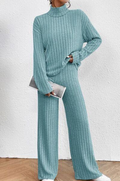 a woman wearing a green sweater and wide legged pants