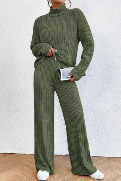 a woman wearing a green sweater and wide legged pants