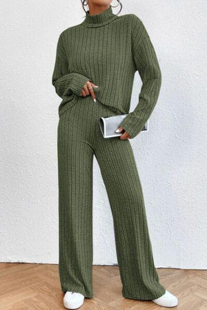a woman wearing a green sweater and wide legged pants