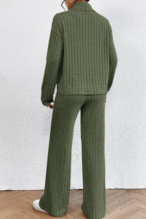 a woman wearing a green sweater and wide legged pants