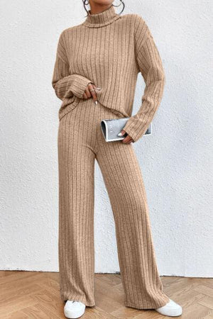 a woman standing in a room wearing a sweater and pants