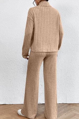 a woman standing in a room wearing a sweater and pants