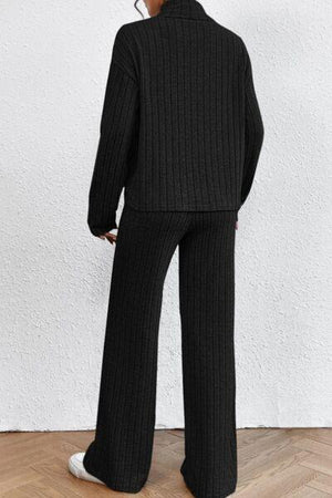 a woman wearing a black sweater and wide legged pants