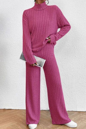 a woman wearing a pink sweater and wide legged pants