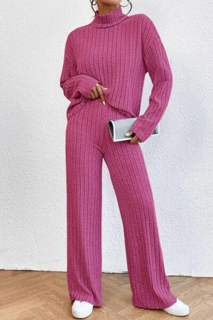 a woman in a pink sweater and wide legged pants