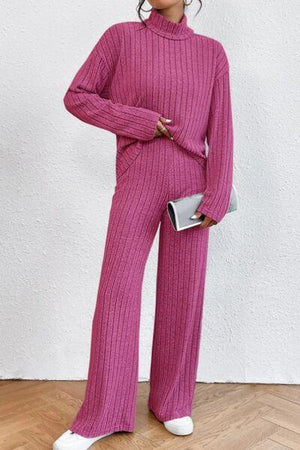 a woman in a pink sweater and wide legged pants
