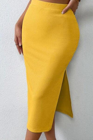 a woman in a yellow skirt leaning against a wall