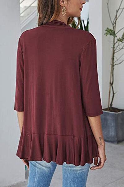 a woman wearing a maroon top with a ruffled hem
