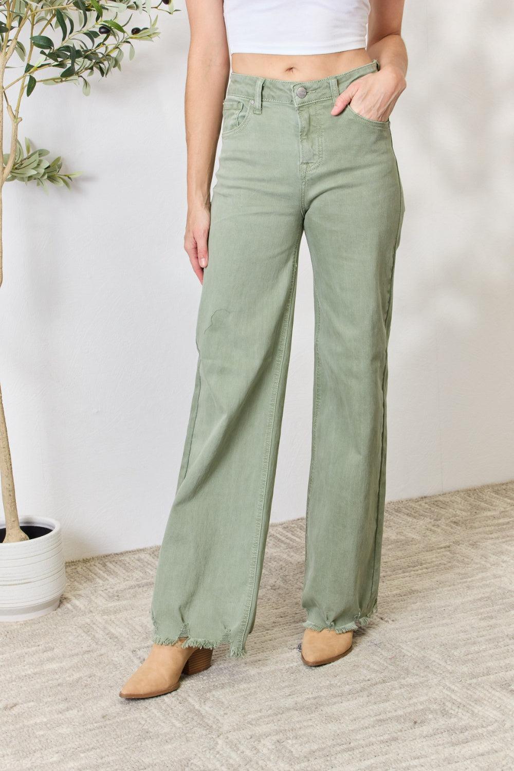 a woman in a white tank top and green pants