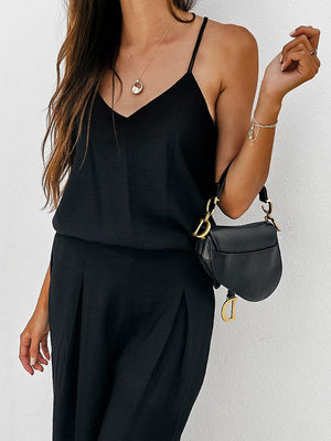 a woman in a black jumpsuit holding a black purse