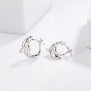 a pair of silver earrings on a white surface