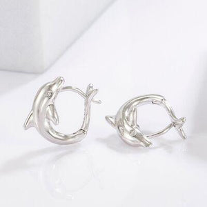 a pair of dolphin earrings sitting on top of a white surface
