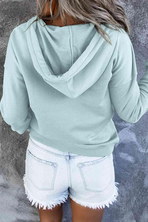 a woman wearing a light blue hoodie and white shorts