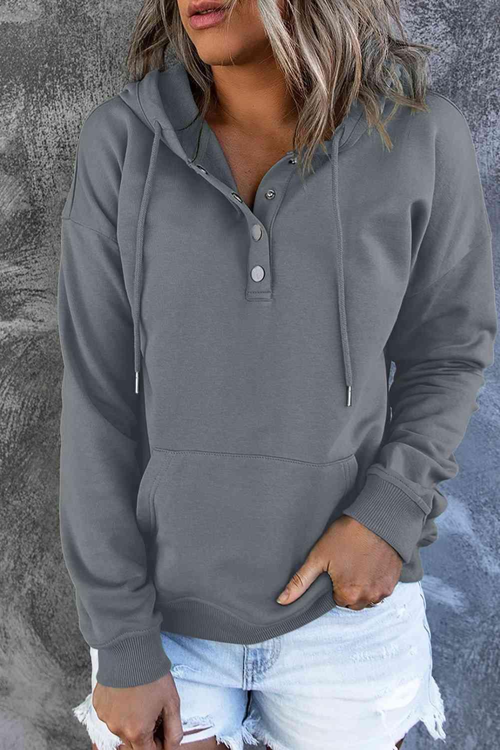 a woman wearing a grey hoodie and ripped shorts