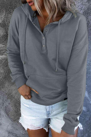 a woman wearing a grey hoodie and ripped shorts