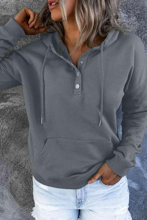 a woman wearing a grey hoodie and ripped jeans