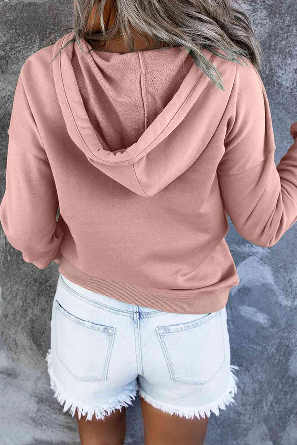a woman wearing a pink hoodie and white shorts