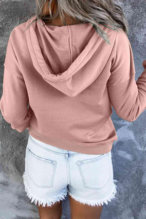 a woman wearing a pink hoodie and white shorts