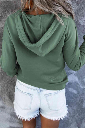 a woman wearing a green hoodie and white shorts