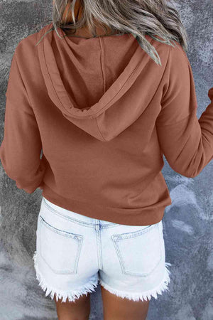a woman wearing a brown hoodie and white shorts