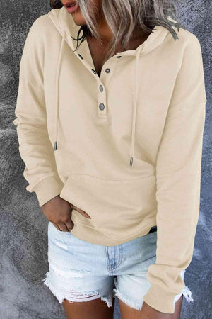 a woman wearing a beige hoodie and ripped shorts
