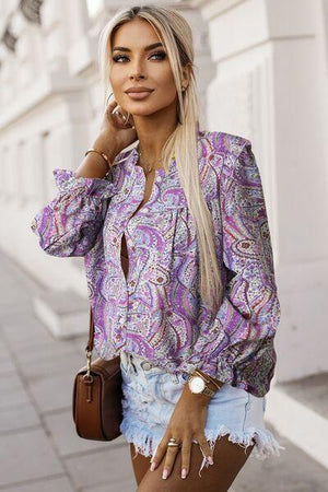 a woman with long blonde hair wearing a purple shirt and denim shorts