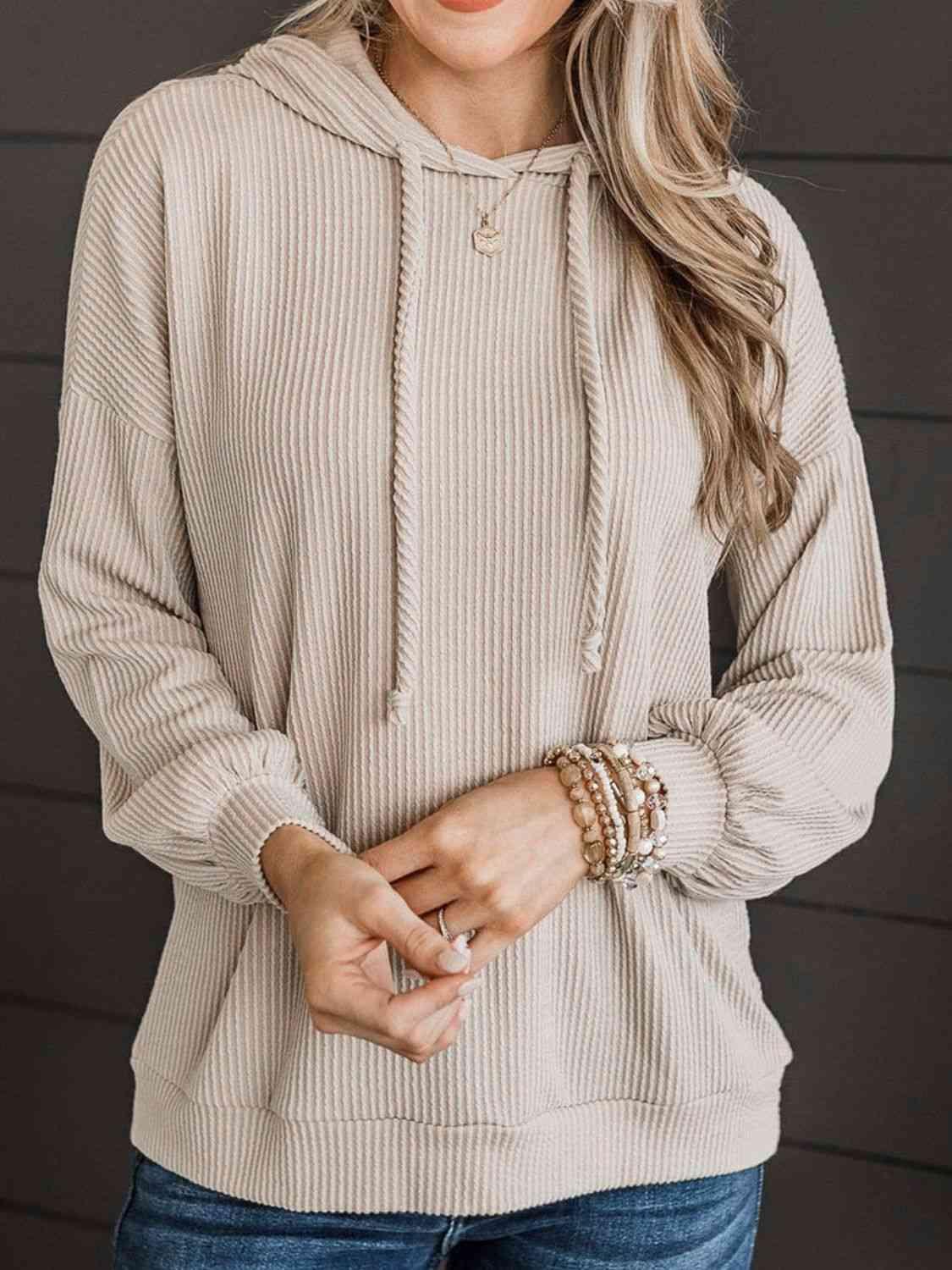 a woman wearing a tan sweater and jeans