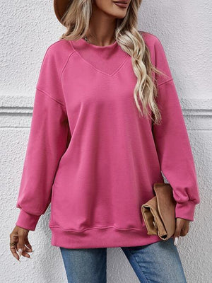 a woman wearing a pink sweatshirt and jeans