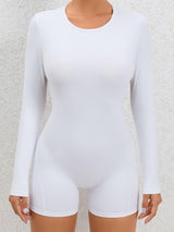 a woman wearing a white bodysuit with long sleeves
